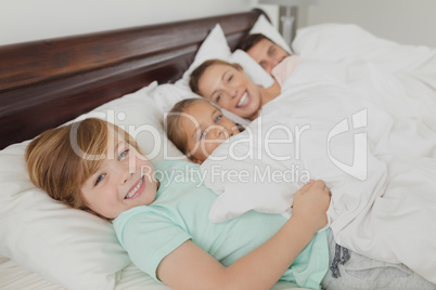 Caucasian family lying together on bed in bedroom at comfortable home
