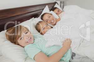 Caucasian family lying together on bed in bedroom at comfortable home