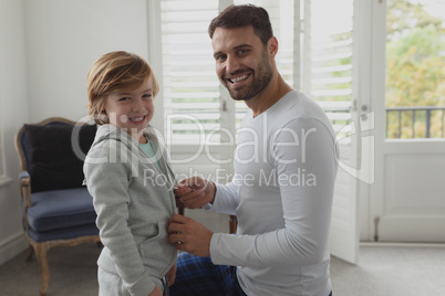 Father helping son putting on clothes
