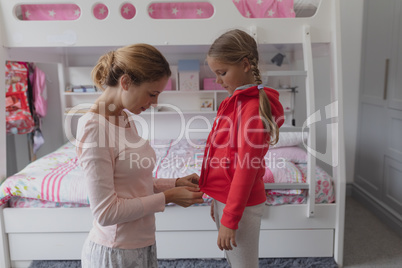 Mother helping daughter putting on clothes