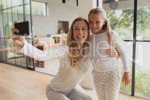 Mother taking selfie with her daughter on mobile phone