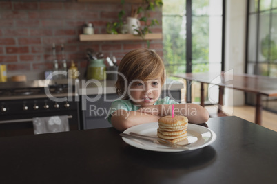 Boy with food sitting at dining table at home