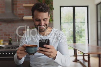 Man with coffee cup using mobile phone