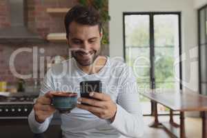 Man with coffee cup using mobile phone