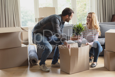 Couple unpacking cardboard box in new home