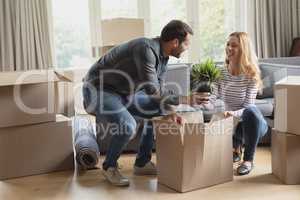 Couple unpacking cardboard box in new home