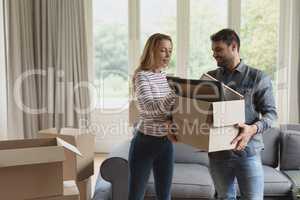 Couple holding cardboard box in new home