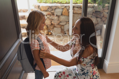 Mother preparing her daughter for school at home