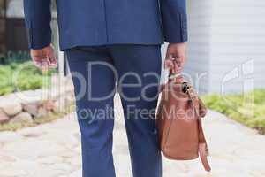 Businessman walking with office bag in the garden