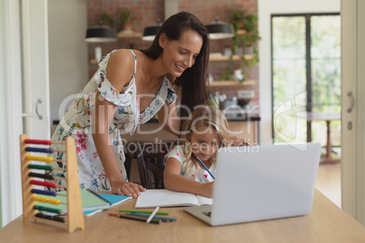 Mother helping her daughter with homework in a comfortable home