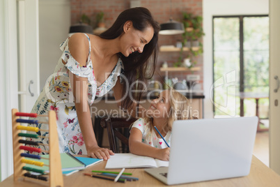 Mother helping her daughter with homework in a comfortable home