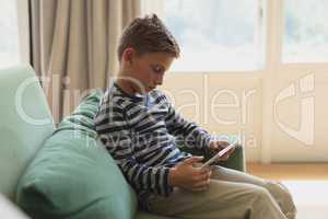 Boy using digital tablet on sofa in a comfortable home