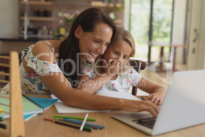 Mother helping her daughter with homework in a comfortable home