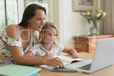 Mother helping her daughter with homework in a comfortable home