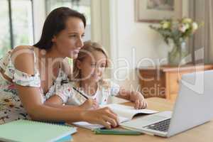 Mother helping her daughter with homework in a comfortable home