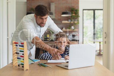 Father helping his son with homework in a comfortable home