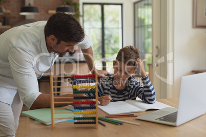 Father helping his son with homework in a comfortable home