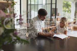 Father helping his daughter with homework in a comfortable home