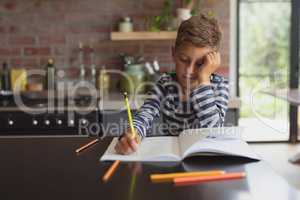 Boy studying at table in kitchen at home