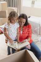 Mother and daughter looking at photo album in living room
