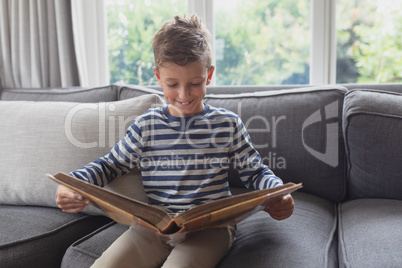 Boy looking at photo album in living room