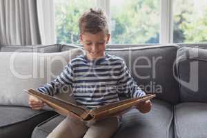 Boy looking at photo album in living room