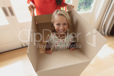 Mother and daughter playing with cardboard box in living room