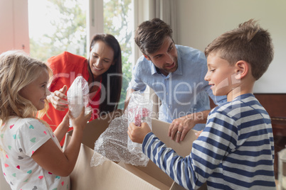 Family unpacking cardboard box in living room