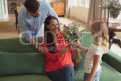 Daughter giving bouquet to mother in living room