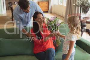 Daughter giving bouquet to mother in living room