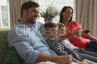 Family watching television in living room at home