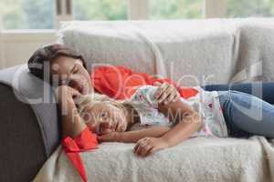 Mother and daughter sleeping together on a sofa in living room