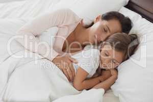 Mother and daughter sleeping in bed in bedroom