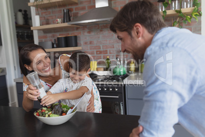 Family preparing vegetable salad in kitchen at home