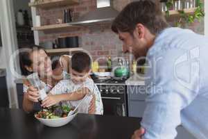 Family preparing vegetable salad in kitchen at home