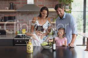 Family preparing vegetable salad in kitchen at home