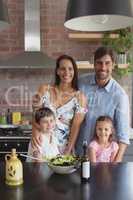 Happy family preparing vegetable salad in kitchen at home