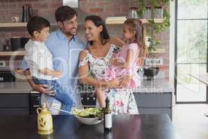 Family preparing vegetable salad in kitchen at home