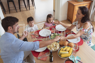 Family praying together before having lunch at dining table