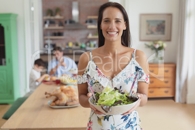 Woman holding a bowl of vegetable salad at home