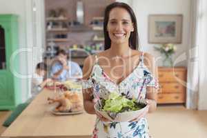 Woman holding a bowl of vegetable salad at home