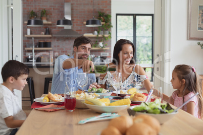 Family having food and champagne on dining table at home