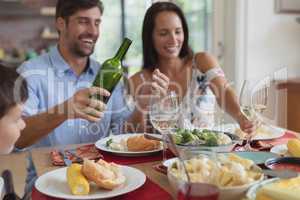 Family having food and champagne on dining table at home