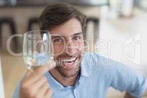 Happy man holding glass of champagne at home