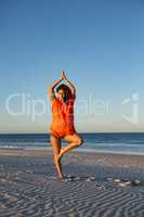 Beautiful woman doing yoga on beach in the sunshine