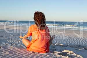 Woman doing yoga on beach in the sunshine