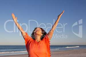 Beautiful woman with arms up standing on beach in the sunshine