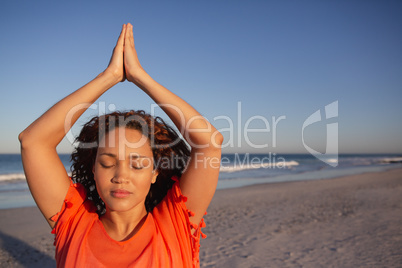 Beautiful woman doing yoga on beach in the sunshine