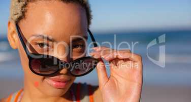 Beautiful woman looking over sunglasses on beach in the sunshine