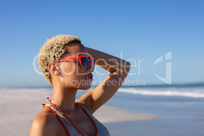 Beautiful woman in sunglasses looking away on beach in the sunshine